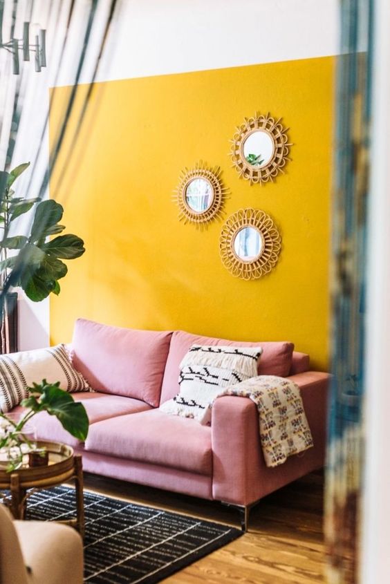 A-colorful-boho-living-room-with-a-sunny-yellow-accent-wall-a-pink-sofa-a-gallery-wall-of-mirrors-and-potted-greenery