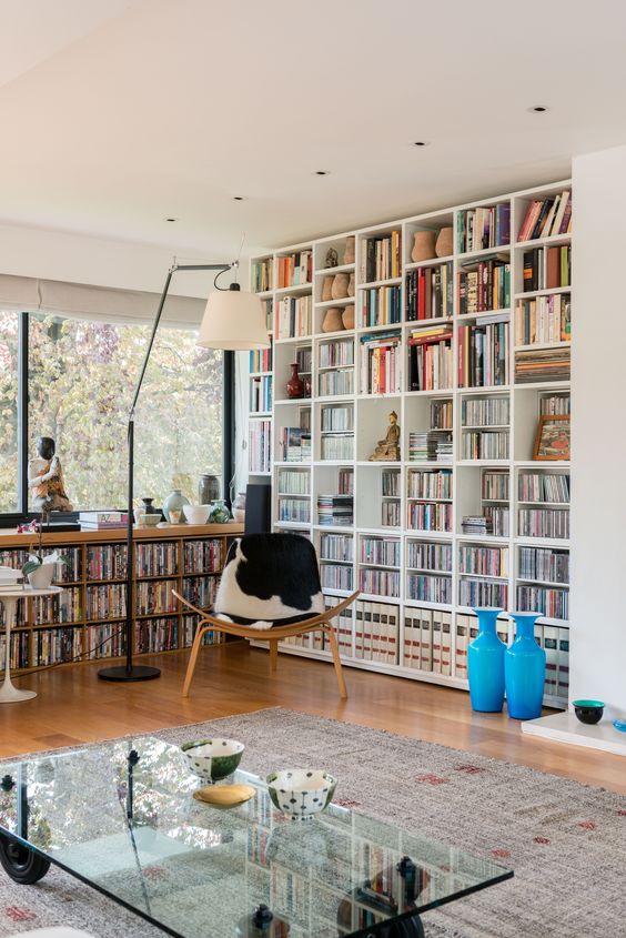 A-modern-home-library-with-a-large-bookcase-and-a-built-in-window-unit-plus-a-cowhide-chair