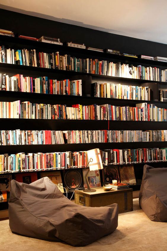 A-modern-home-library-with-dark-bookshelves-and-a-couple-of-beanbag-loungers-plus-enough-light-to-read