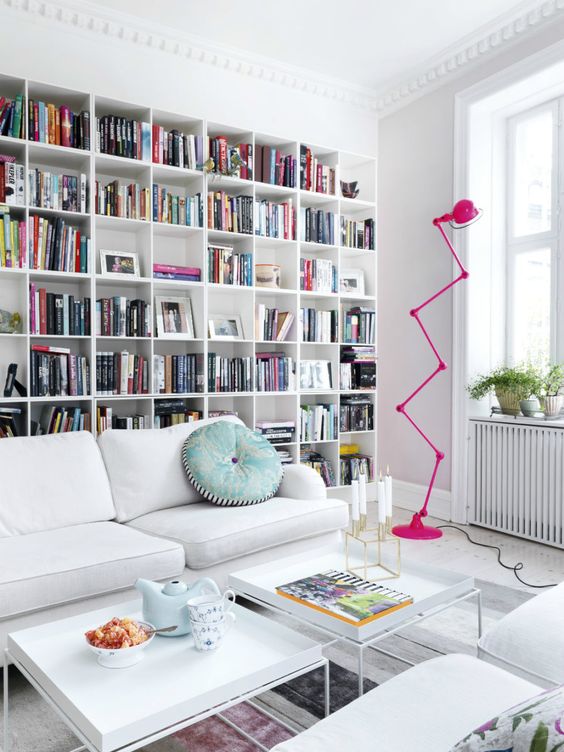 A-stylish-modern-library-with-a-large-built-in-bookcase-white-furniture-and-a-whimsy-hot-pink-floor-lamp