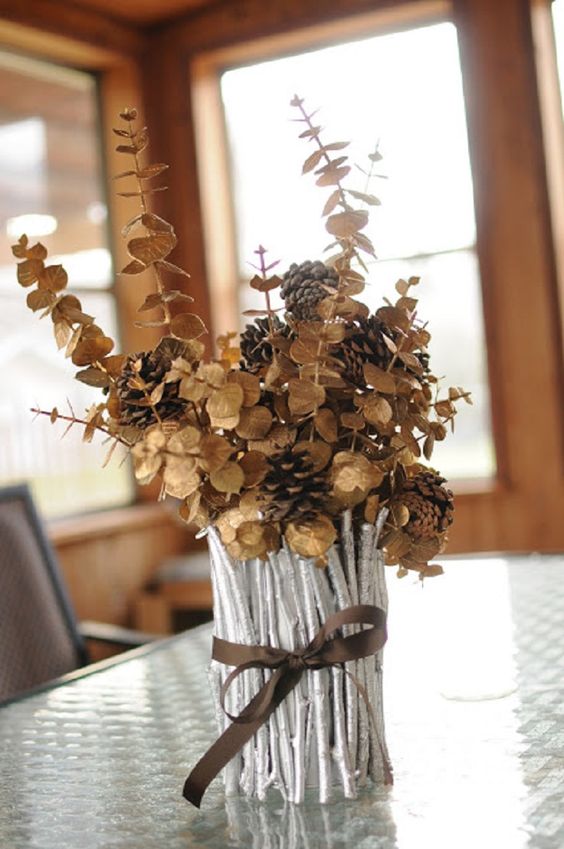 A-vase-covered-with-silver-painted-sticks-and-twigs-dried-eucalyptus-and-pinecones-is-a-chic-fall-centerpiece-1