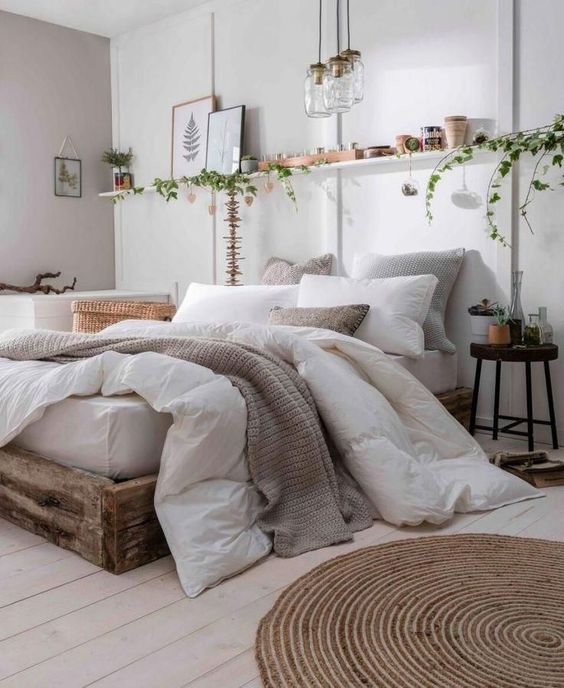 1-a-neutral-boho-bedroom-with-a-rough-wooden-bed-a-jute-rug-an-open-shelf-pendant-lamps-and-greenery