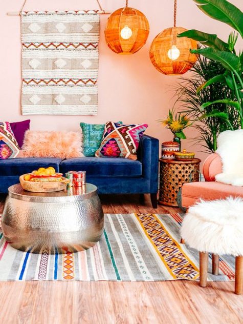 A-colorful-boho-living-room-with-bright-lampshades-pink-walls-boho-rugs-and-pillows-and-a-hammered-metal-coffee-table