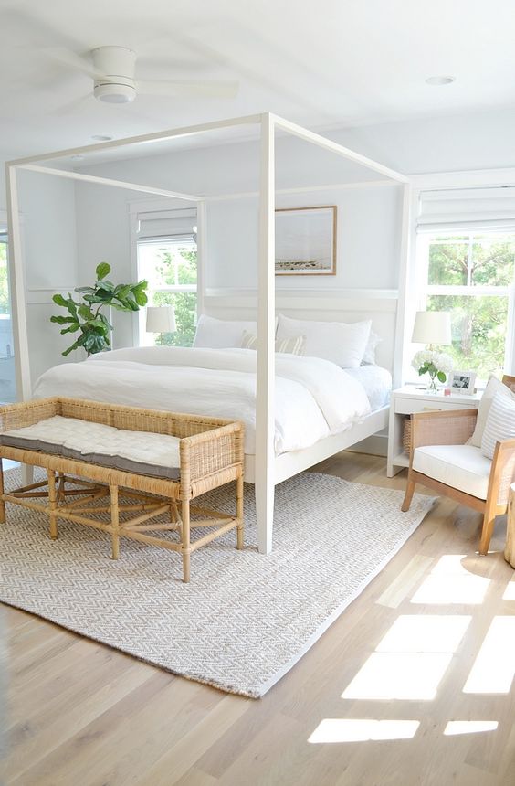 A-stylish-modern-neutral-bedroom-with-a-white-canopy-bed-a-woven-bench-chairs-and-neutral-textiles