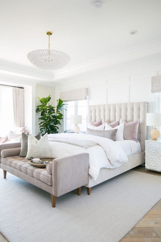 An-elegant-neutral-bedroom-with-a-creamy-bed-neutral-and-pastel-bedding-a-pastel-bench-and-a-statement-plant