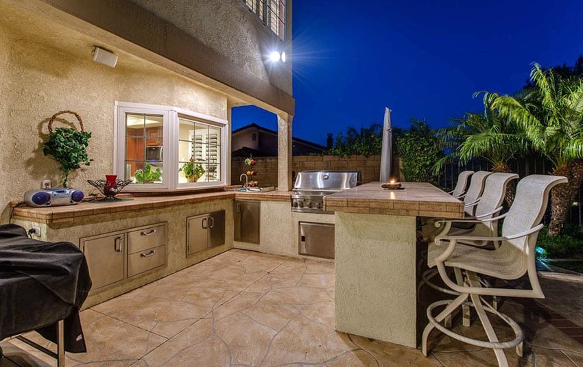 Outdoor-kitchen-with-bar-stool-seating-on-stone-patio