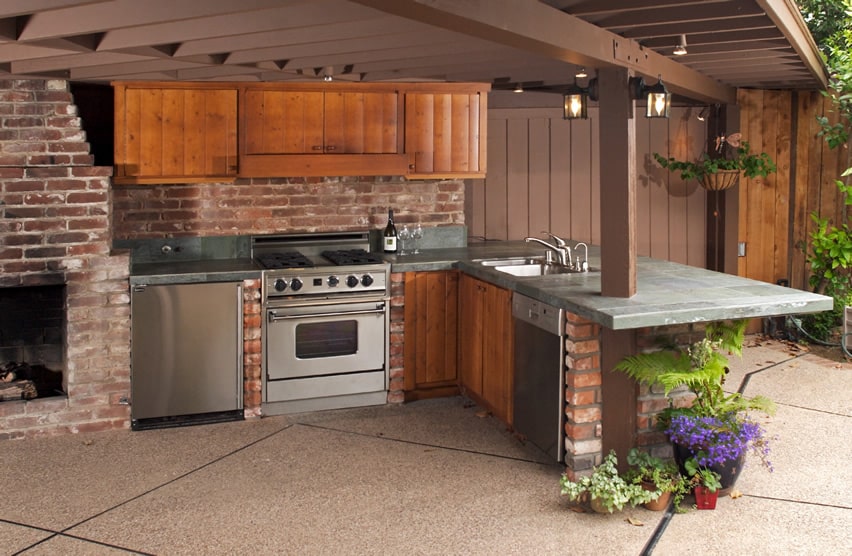 Outdoor-kitchen-with-brick-fireplace-wood-cabinets