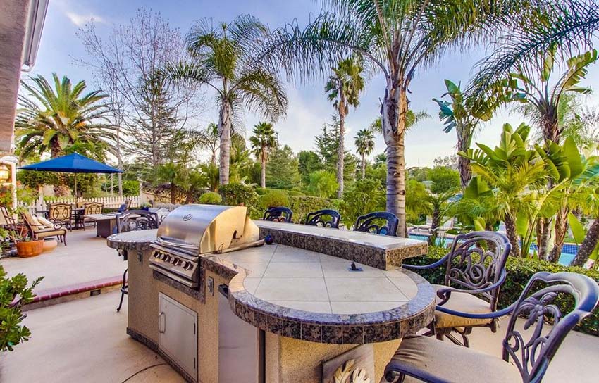 Outdoor-kitchen-with-curved-countertop-and-bar-stool-seating-overlooking-swimming-pool-1