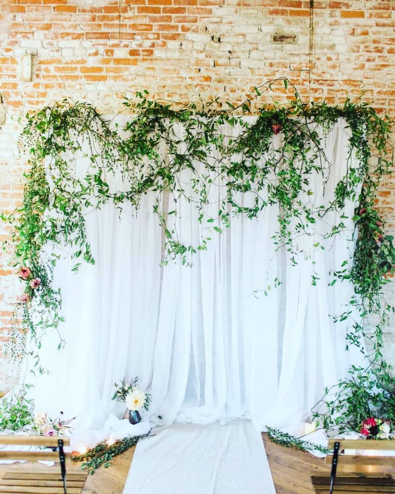 White-draped-wedding-backdrop-with-draped-greenery-768x960-1