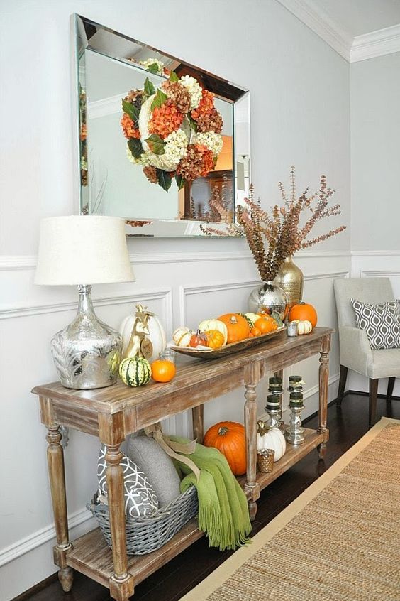05-a-rustic-console-table-with-pumpkins-on-display-and-a-colorful-fall-wreath-over-it