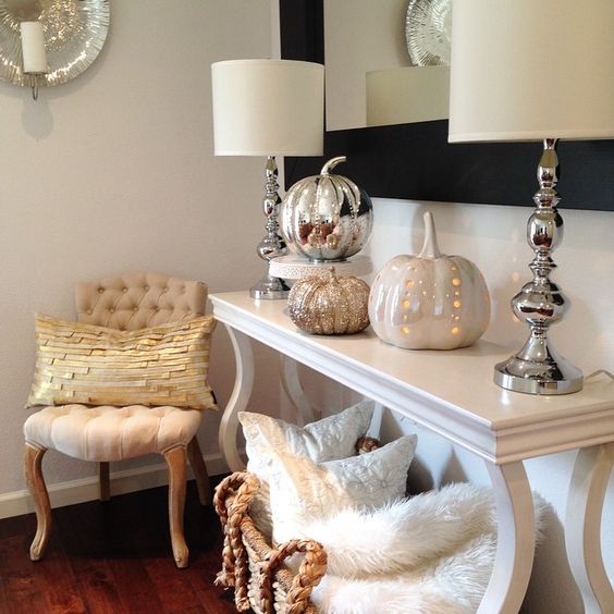 06-a-console-table-with-various-shiny-pumpkins-and-a-wicker-basket-with-pillows-and-faux-fur