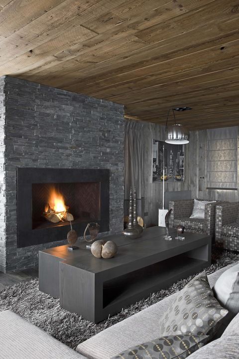 1-a-masculine-living-room-with-a-stone-clad-fireplace-wooden-tables-a-faux-fur-rug-upholstered-furniture-and-lamps