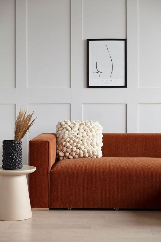 29-a-refined-modern-space-with-off-white-paneled-walls-a-terracotta-sofa-a-pompom-pillow-and-a-matching-vase