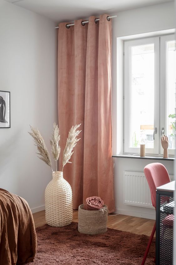 34-a-warm-colored-space-with-a-brown-rug-and-a-bedspread-a-pink-chair-and-rust-colored-curtains-that-add-warmth-here