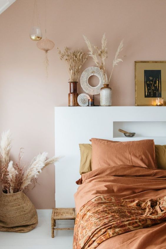 36-an-inviting-boho-bedroom-with-a-pale-brown-wall-a-bed-with-terracotta-bedding-grasses-in-vases-and-candles-is-cool