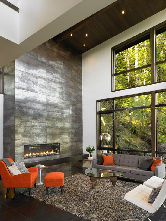 Stone-wall-fireplace-dark-wood-floor-shaggy-carpet-gray-orange-armchair
