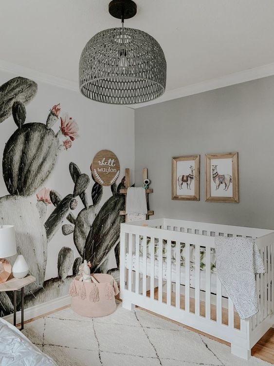 A-boho-desert-nursery-with-a-cactus-wall-a-pink-tassel-basket-a-grey-rattan-lamp-and-llama-artworks-over-the-crib