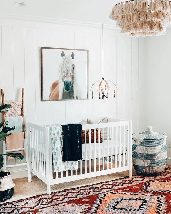 A-bright-boho-nursery-with-a-colorful-rug-a-printed-basket-with-a-lid-a-macrame-chandelier-colorful-textiles-and-a-horse-artwork