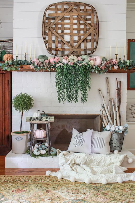 A-bright-fall-mantel-with-cascadign-greenery-pastel-pumpkins-greenery-branches-in-a-bucket-and-a-wooden-basket