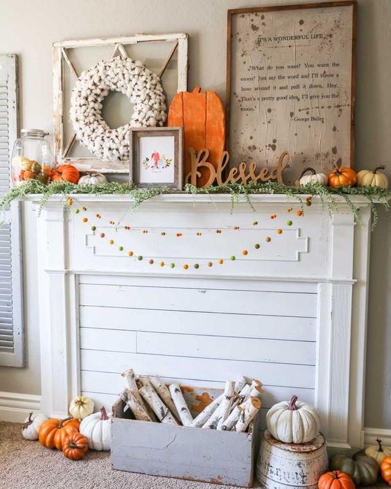 A-bright-rustic-flal-mantel-with-colorful-pompom-garlands-a-crate-with-birch-branches-lots-of-pumpkins-signs-and-a-cotton-wreath