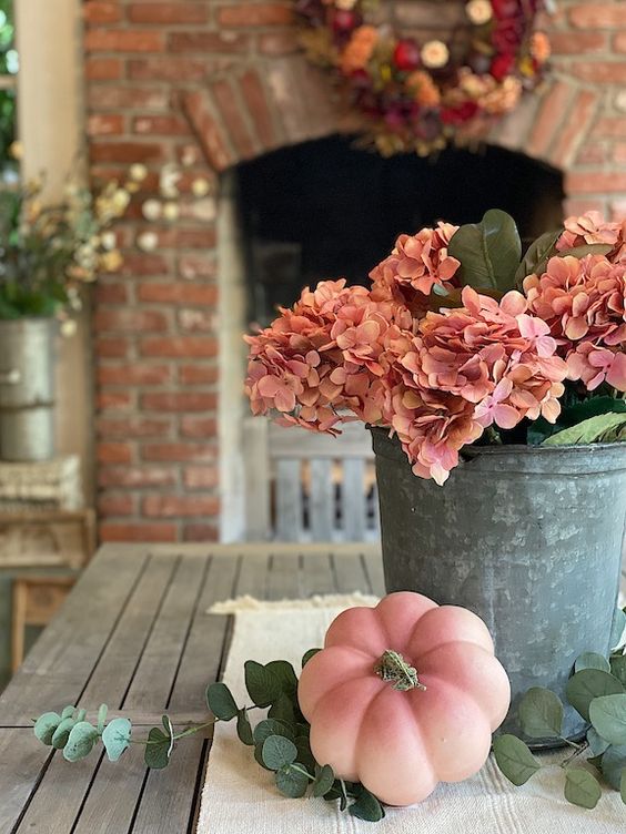 A-bucket-with-pink-hydrangeas-and-leaves-plus-a-matching-pink-pumpkin-next-to-it-is-a-stylish-rustic-idea