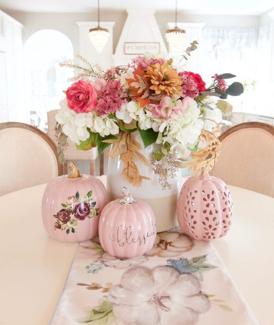 A-chic-and-bright-fall-flower-arrangement-of-white-pink-rust-blooms-and-greenery-and-pink-faux-pumpkins