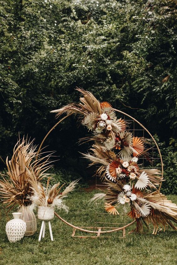 A-chic-modern-boho-wedding-arch-decorated-with-dried-colorful-leaves-and-fronds-and-pastel-blooms