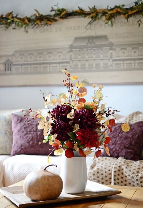 A-colorful-fall-arrangement-of-leaves-branches-with-berries-faux-bright-blooms-and-a-large-veggie-next-to-it