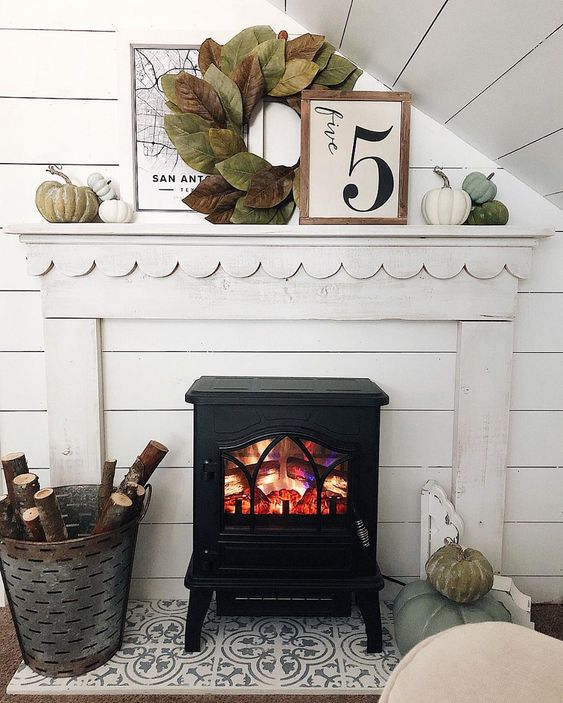 A-cozy-fall-mantel-with-a-large-leaf-wreath-muted-pumpkins-and-branches-in-the-bucket