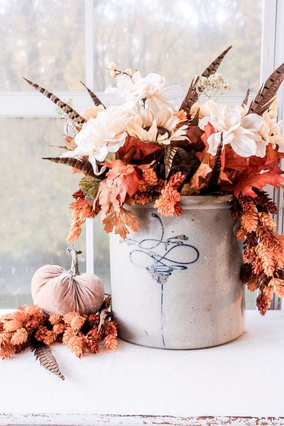 A-fantastic-fall-boho-centerpiece-of-white-blooms-fall-leaves-feathers-in-a-bucket-is-a-very-bold-and-chic-idea