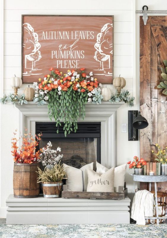 A-lush-fall-mantel-with-pale-greenery-faux-pumpkins-gorgeous-florals-and-cascading-greenery-fall-leaves-and-cotton-in-buckets-and-a-fall-sign