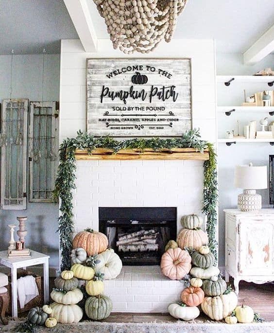 A-modern-farmhouse-mantel-with-stacks-of-heirloom-pumpkins-a-greenery-wreath-and-a-large-rustic-sign