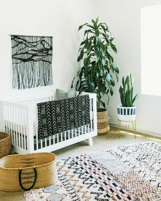 A-monochromatic-boho-nursery-with-a-black-macrame-hanging-a-printed-rug-a-folksy-print-blanket-and-potted-plants