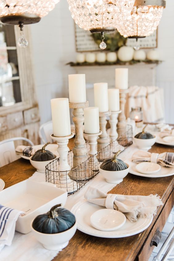 A-neutral-farmhouse-chic-tablescape-with-dark-fabric-pumpkins-wooden-candleholders-and-striped-napkins
