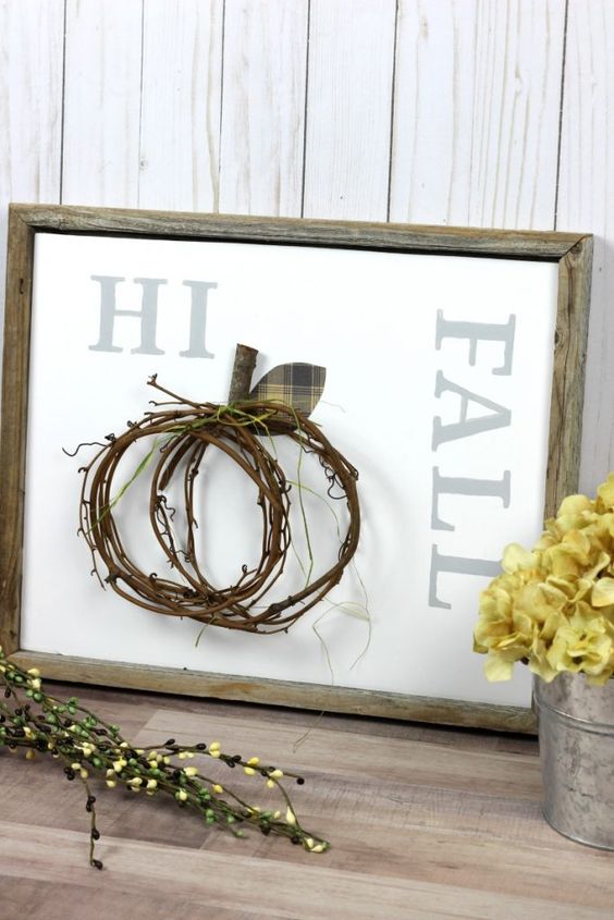 A-non-typical-fall-sign-in-a-reclaimed-wooden-frame-a-twig-pumpkin-attached-and-yellow-blooms-next-to-it