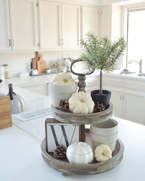 A-reclaimed-wooden-stand-with-white-and-porcelain-pumpkins-pinecones-a-potted-plant-and-a-letter-sign