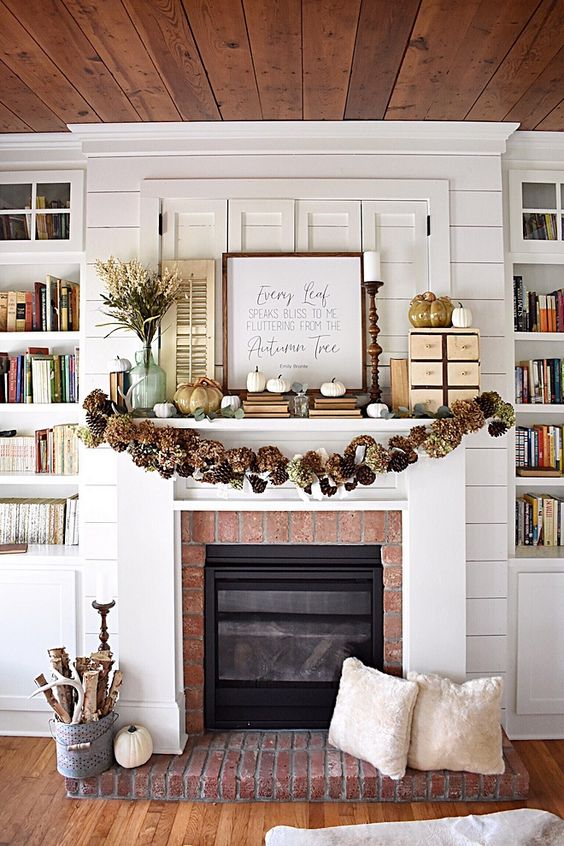 A-rustic-fall-mantel-with-a-pinecone-and-hydrangea-garland-white-pumpkins-and-faux-porcelain-ones-a-branch-arrangement-in-a-bucket