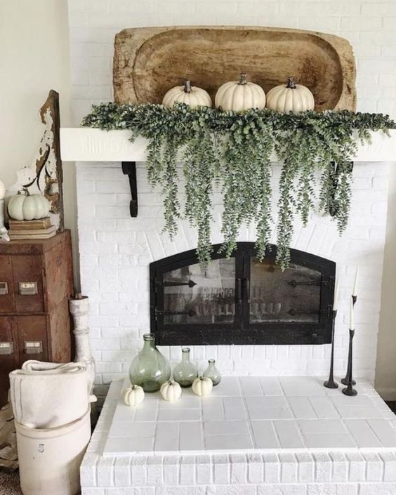 A-rustic-fall-mantel-with-cascading-greenery-white-pumpkins-with-a-wooden-dough-bowl-plus-green-bottles