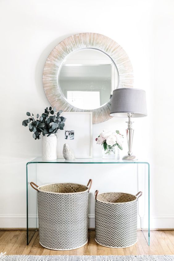 A-sheer-acrylic-console-a-couple-of-patterned-baskets-for-storage-a-wood-clad-mirror-and-a-chic-lamp