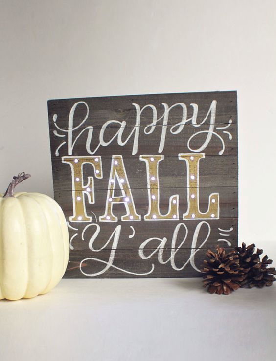 A-stained-wooden-sign-with-white-and-gold-letters-is-a-chic-and-cute-mantel-decoration-for-the-fall