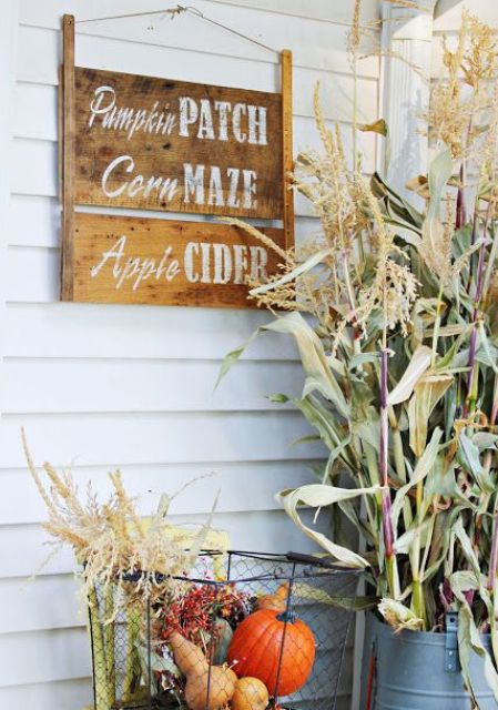 A-stained-wooden-sign-with-white-letters-and-a-wire-basket-with-fall-veggies-and-greenery-for-a-fall-touch