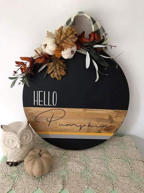 A-stylish-round-fall-sign-done-with-staining-and-black-paint-topped-with-leaves-yarn-pumpkins-and-plaid-ribbon