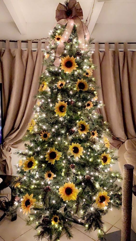 A-sunflower-thanksgiving-tree-with-lights-pinecones-blooms-and-a-large-taupe-bow-on-top