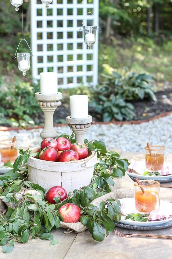 A-wooden-basket-with-red-apples-and-lush-foliage-a-couple-of-candles-in-wooden-candleholders-for-a-fall-centerpiece