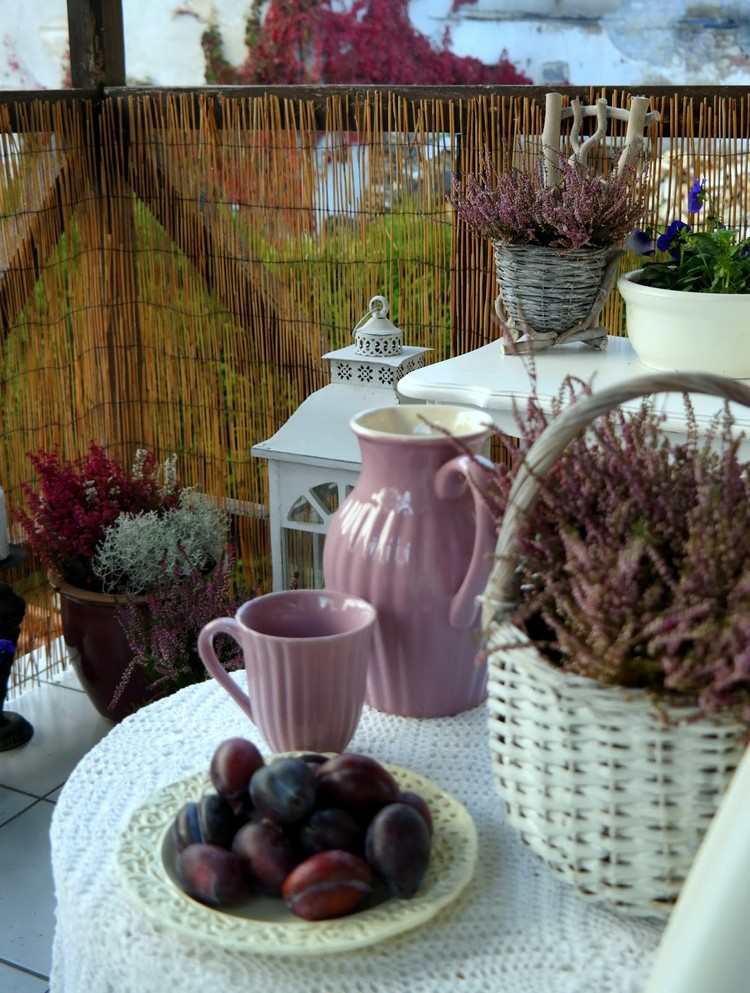 Balkon-herbstlich-dekorieren-weisse-koerbe-haeckel-tischdecke-pflaumen-eriken