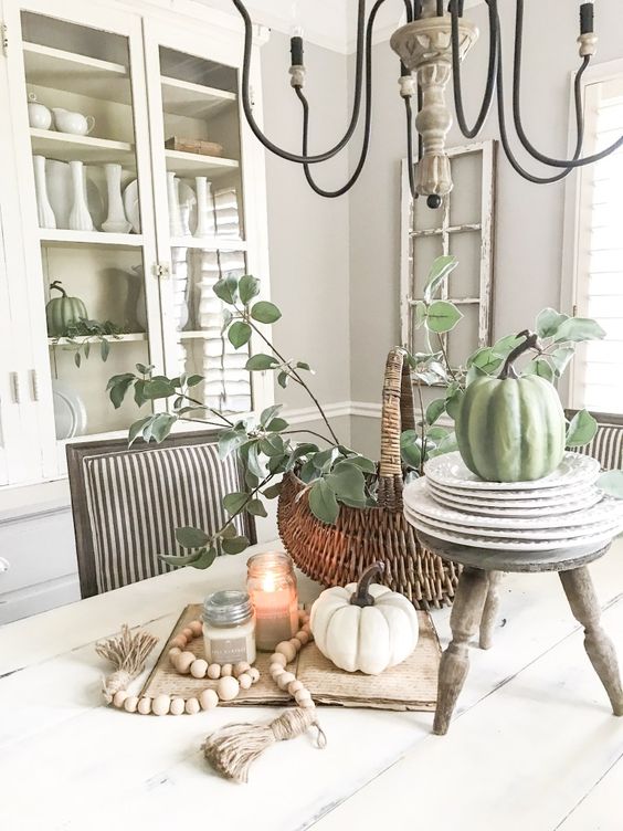 Fall-kitchen-decor-with-white-and-green-pumpkins-candles-wooden-beads-and-a-basket-with-greenery