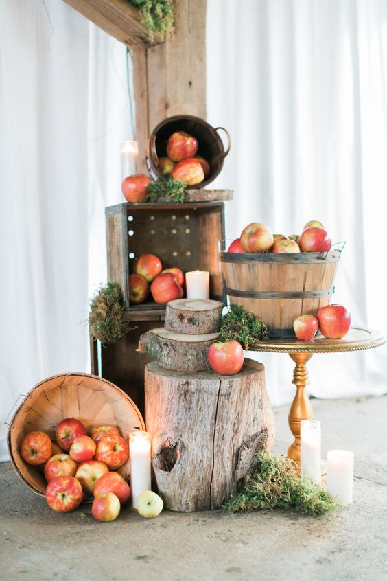 Pretty-woodland-and-rustic-decor-with-apples-in-wooden-baskets-moss-tree-slices-and-stumps-candles-on-the-floor