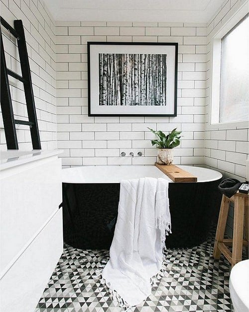 Beautiful-black-and-white-bathroom-with-white-subway-tiles-black-grout-graphic-geometric-patterned-floor-black-freestanding-bathtub-and-modern-fine-art-photography