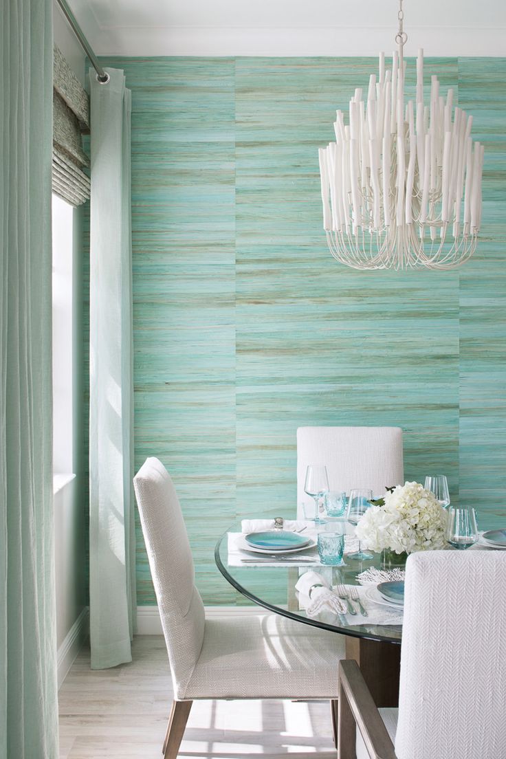 Diningroomfeaturingvibrantturquoisegrassclothwallpaperwhitechandelierglassdiningtableandwhitediningchairs