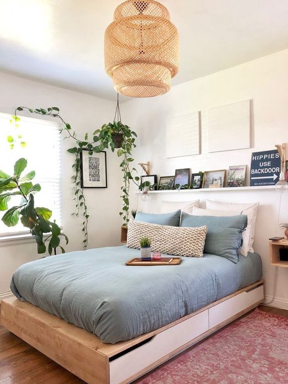 A-contemporary-small-bedroom-with-a-storage-bed-a-ledge-with-a-gallery-wall-a-wicker-lamp-and-potted-greenery